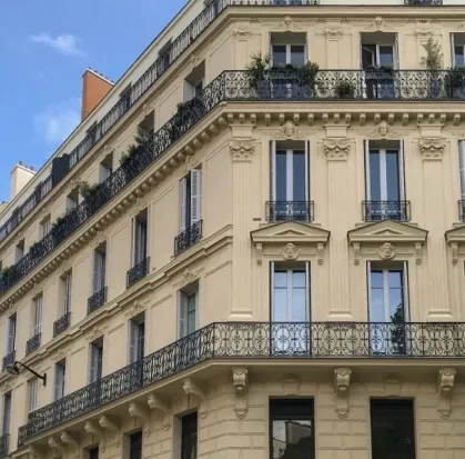 Façade d’un immeuble ancien avec balcons et garde-corps en fer forgé.
