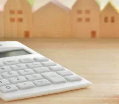 Calculatrice posée devant des maisons miniatures.
