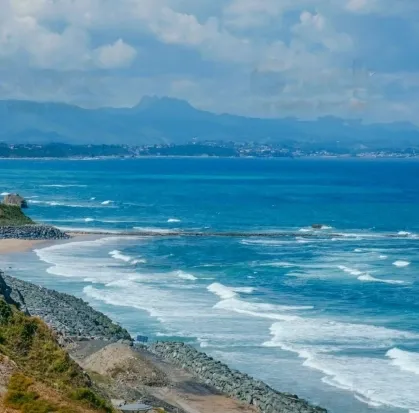 Littoral rocheux bordé par une plage et les vagues de l’océan.